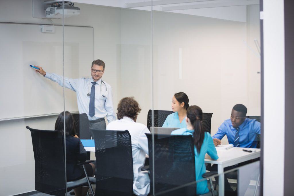 Doctor Giving Presentation To Team Of Interim Doctors At Conference Room